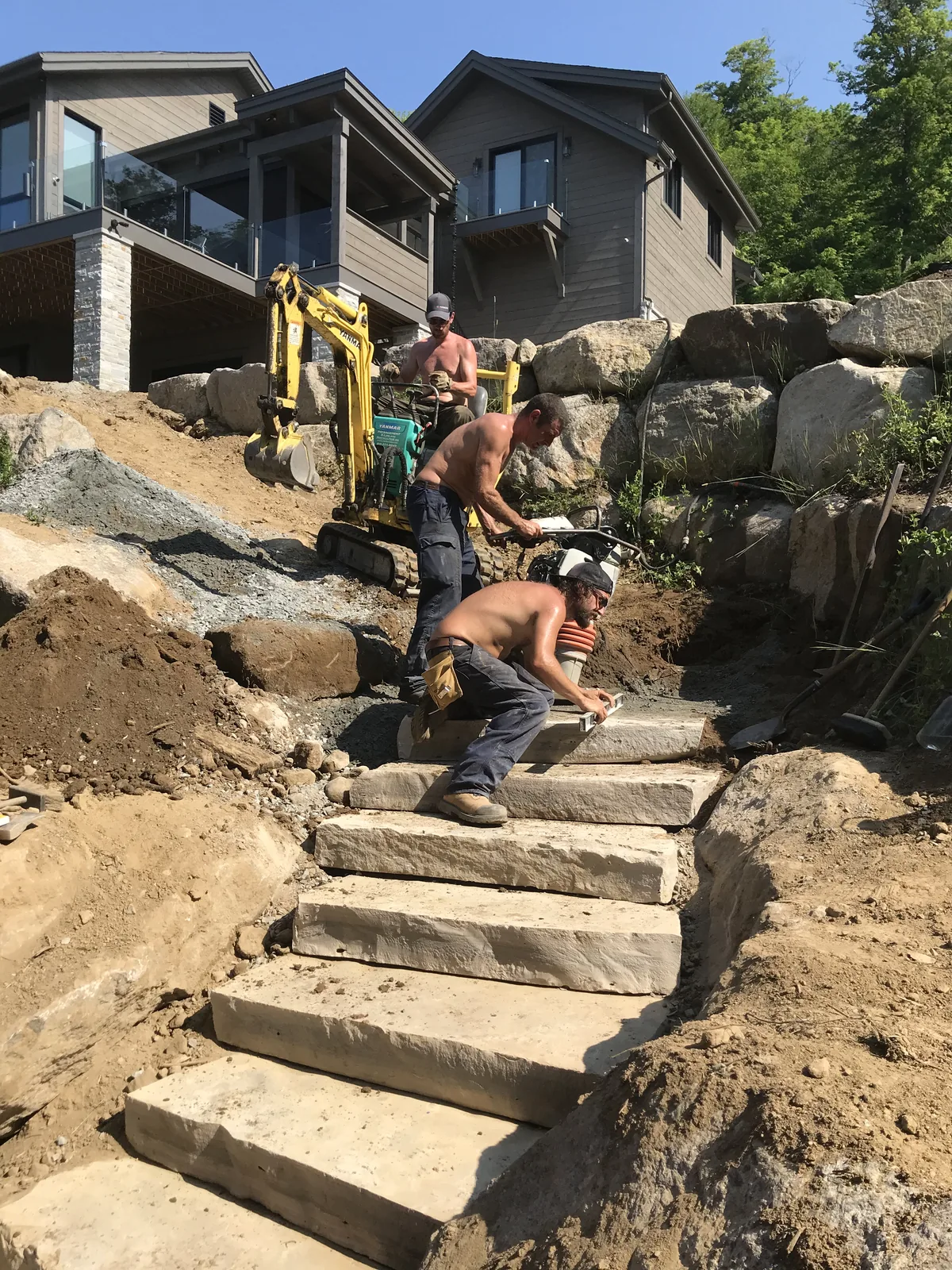 Aménagement d'un escalier de pierre dans la pente du terrain, sous une résidence contemporaine