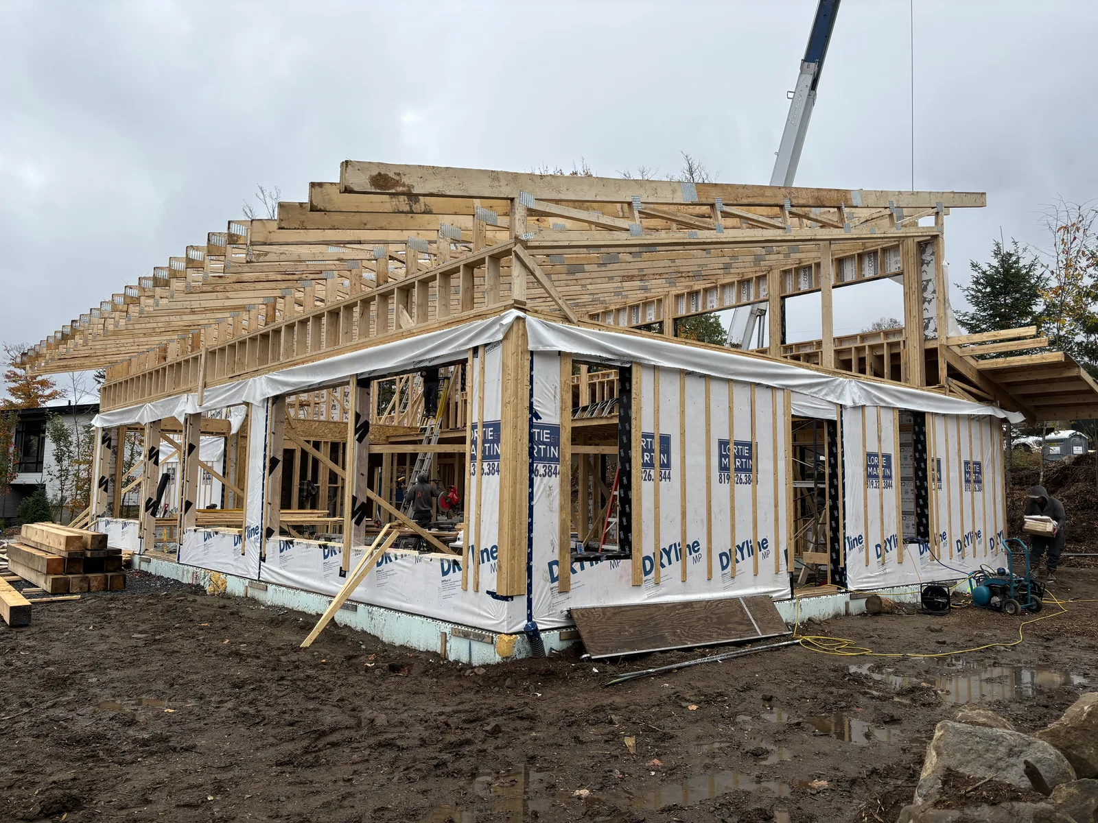 Charpente de bois d'une résidence sur mesure en construction, fermes de toit apparentes et grue